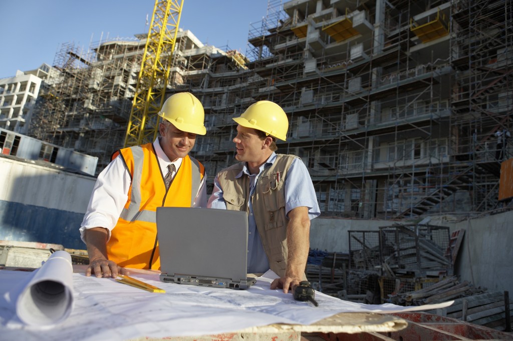 Two Men Wearing Hard Hats Looking at a Laptop Computer on a Building Site